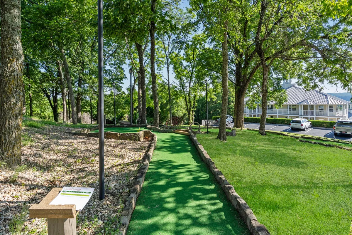 A playful mini-golf course winds through shady trees, with clear signage and inviting paths. The landscaped setting is family-friendly, energetic, and ideal for group fun or bonding moments.
