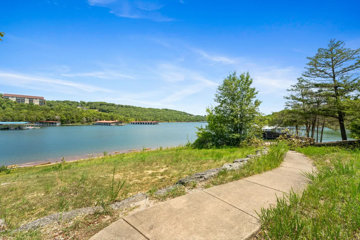 A sweeping view of a serene lake framed by verdant hills and a winding pathway. The placid water and untouched landscape conjure a sense of calm and reconnection with nature, perfect for quiet walks, reflection, or lakeside activities mentioned in the section.