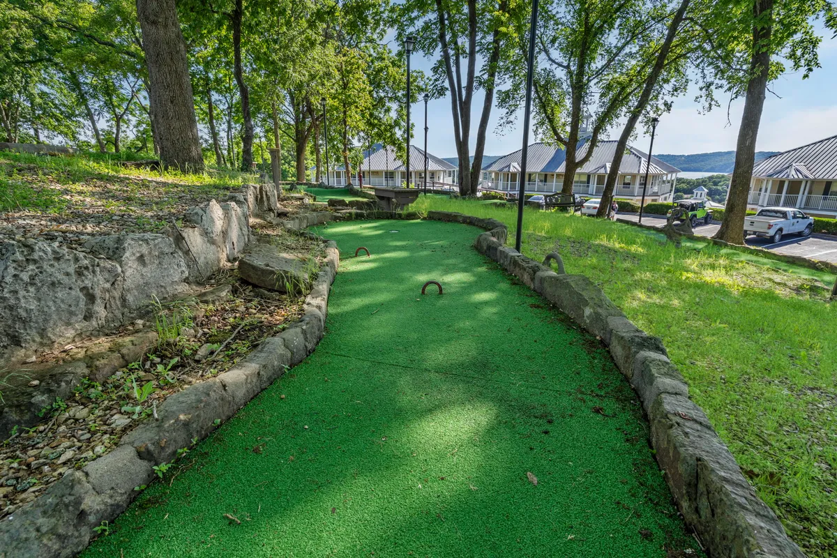 A cheerful mini-golf course nestled among lush greenery and natural rock formations, with winding pathways inviting families for friendly competition and outdoor fun.