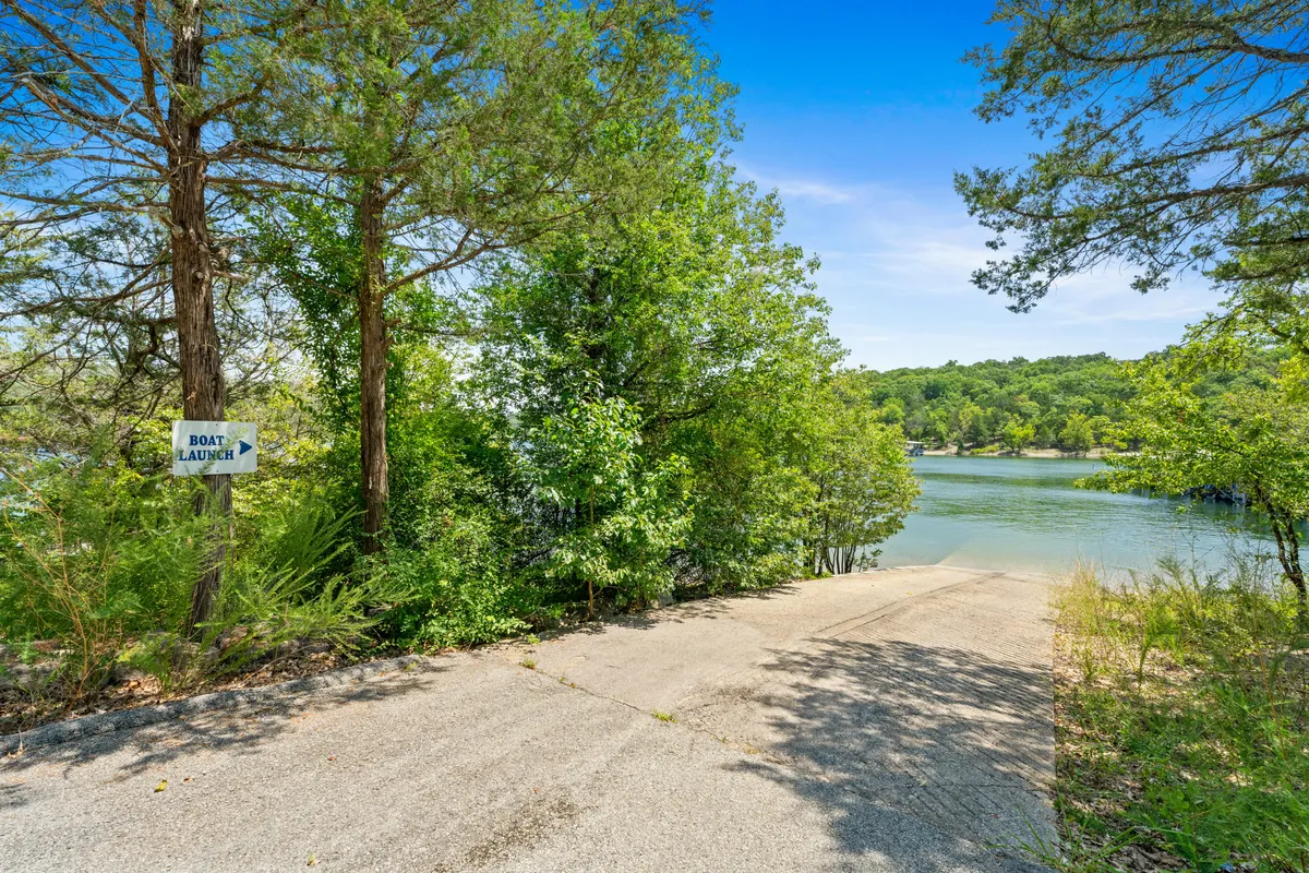 A peaceful waterfront scene featuring a boat launch sign, gently rippling water, and a green tree line. The serene vibe suggests opportunities for private boat rides and lakeside relaxation, directly aligning with the section’s mention of boating and outdoor leisure.