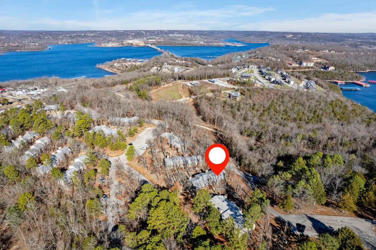 A peaceful lakeside scene with wooded areas, scattered houses, and winding roads. The expansive lake is the central feature, bordered by trees—an ideal setting for lakeside strolls, nature walks, and outdoor play sessions with pets. The quiet, natural environment is emphasized, inviting guests to explore with their furry companions.